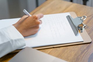 Ärztin notiert etwas auf einem Klemmbrett